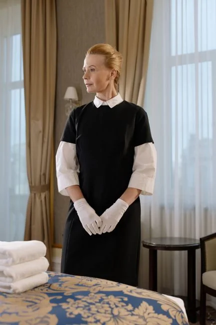 who-we-are A housekeeper elegantly arranges bed sheets in a luxurious hotel room, showcasing hospitality expertise.